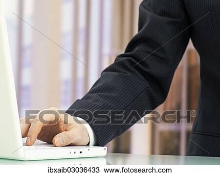 Stock Image - "Businessman, detail of an arm using a laptop". Fotosearch