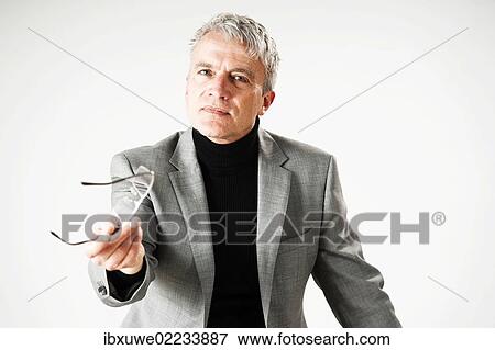 Businessman gesticulating in a specific direction whilst holding his glasses View Large Photo Image Stock Photo - Businessman gesticulating in a specific direction whilst holding his glasses. Fotosearch