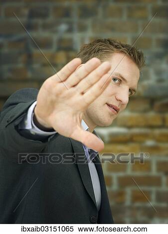 Businessman holding a hand up in a defensive manner View Large Photo Image Stock Photography - Businessman holding a hand up in a defensive manner. Fotosearch