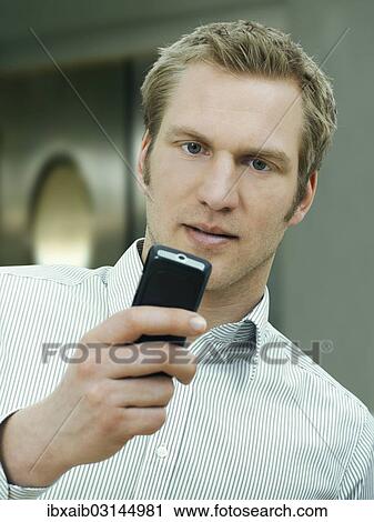 Stock Image - Businessman holding a mobile phone. Fotosearch