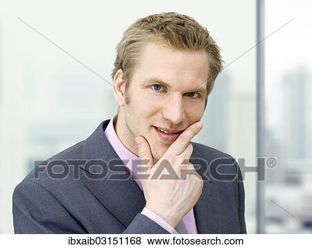 Businessman holding his hand on his chin View Large Photo Image Stock Photo - Businessman holding his hand on his chin. Fotosearch