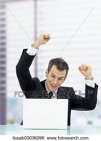 Businessman in an office cheering from behind a laptop View Large Photo Image Stock Photograph - Businessman in an office cheering from behind a laptop. Fotosearch