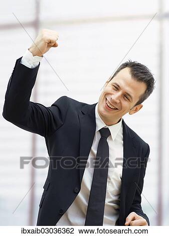 Businessman in an office cheering with a clenched fist View Large Photo Image Stock Image - Businessman in an office cheering with a clenched fist. Fotosearch
