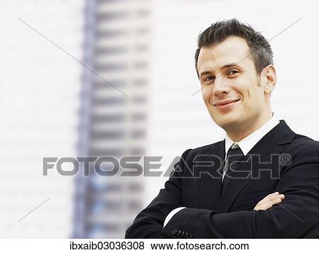 Stock Photo - "Businessman in an office, smiling, with his arms crossed". Fotosearch