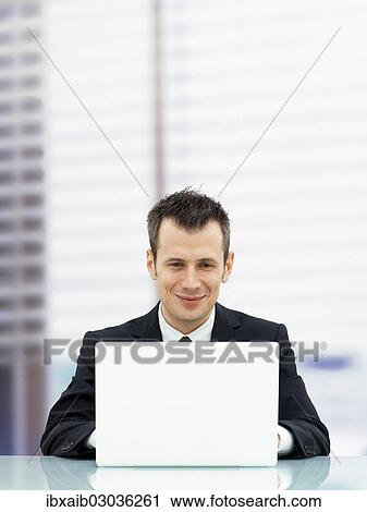 Stock Image - Businessman in an office with a laptop. Fotosearch