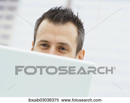 Businessman in an office with a laptop View Large Photo Image Stock Photography - Businessman in an office with a laptop. Fotosearch