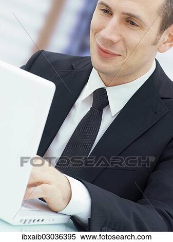 Businessman in an office with a laptop View Large Photo Image Stock Photography - Businessman in an office with a laptop. Fotosearch