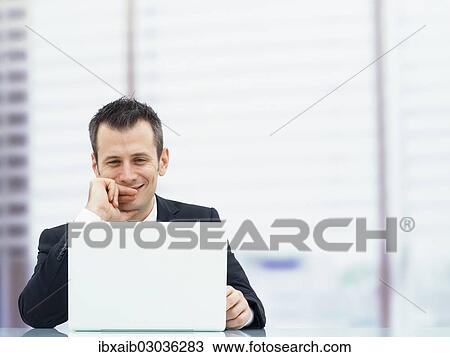 "Businessman in an office with a laptop, looking relaxed and smiling" View Large Photo Image Stock Image - "Businessman in an office with a laptop, looking relaxed and smiling". Fotosearch