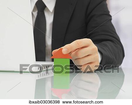 "Businessman in an office with a laptop, building a house out of blocks" View Large Photo Image Stock Photo - "Businessman in an office with a laptop, building a house out of blocks". Fotosearch