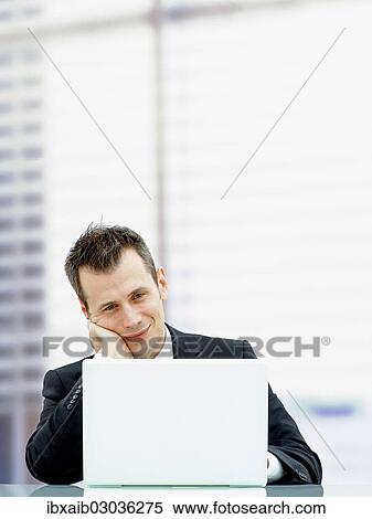 "Businessman in an office with a laptop, looking relaxed and smiling" View Large Photo Image Stock Photography - "Businessman in an office with a laptop, looking relaxed and smiling". Fotosearch
