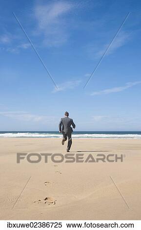 Stock Photography - Businessman jogging along the beach. Fotosearch