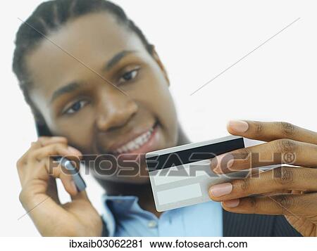 Stock Image - "Businessman, talking on a telephone and holding a credit card". Fotosearch