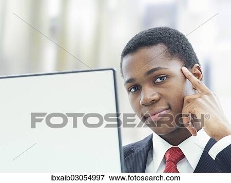 Businessman using a laptop in an office View Large Photo Image Stock Photo - Businessman using a laptop in an office. Fotosearch
