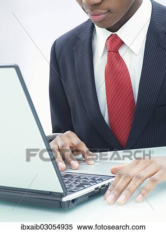 Businessman using a laptop in an office View Large Photo Image Stock Photography - Businessman using a laptop in an office. Fotosearch