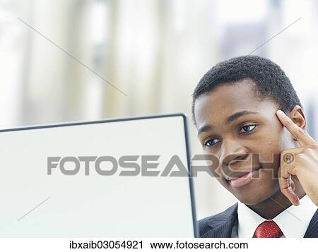 Stock Image - "Businessman using a laptop in an office, concentrating". Fotosearch