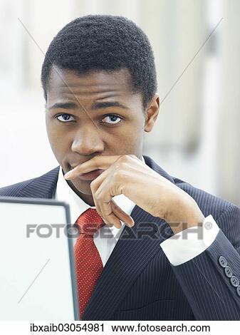 Stock Image - "Businessman using a laptop in an office, serious, thoughtful". Fotosearch