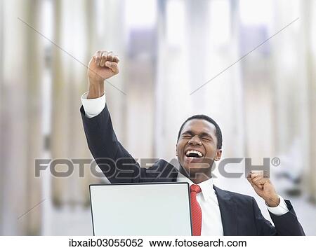 "Businessman using a laptop in an office, jubilating" View Large Photo Image Stock Image - "Businessman using a laptop in an office, jubilating". Fotosearch