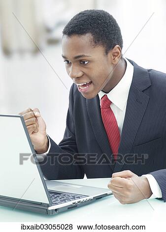 "Businessman using a laptop in an office, jubilating" View Large Photo Image Stock Photo - "Businessman using a laptop in an office, jubilating". Fotosearch