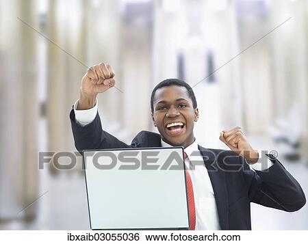 Stock Photograph - "Businessman using a laptop in an office, jubilating". Fotosearch