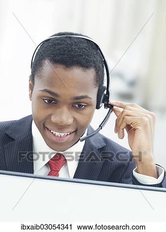 Stock Image - "Businessman, wearing a headset in an office". Fotosearch