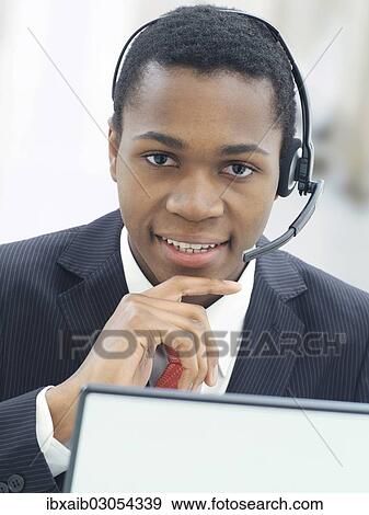 Stock Photo - "Businessman, wearing a headset in an office". Fotosearch