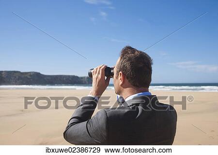 Businessman with binoculars at the beach View Large Photo Image Stock Photo - Businessman with binoculars at the beach. Fotosearch