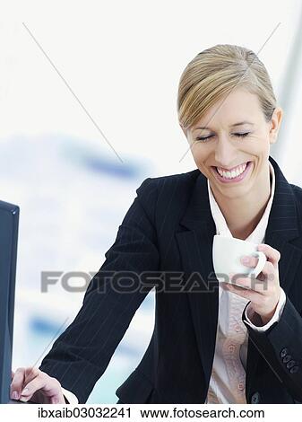 "Businesswoman at the office, holding a cup of coffee, relaxed" View Large Photo Image Stock Image - "Businesswoman at the office, holding a cup of coffee, relaxed". Fotosearch