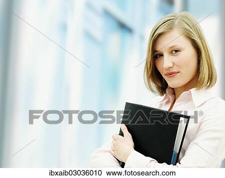 Stock Image - Businesswoman holding a ring binder. Fotosearch