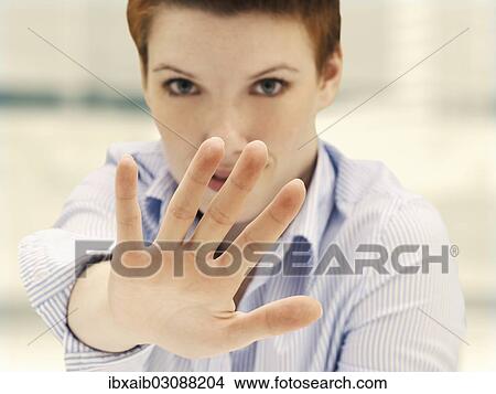 Businesswoman in an office making a defensive gesture with a raised hand View Large Photo Image Picture - Businesswoman in an office making a defensive gesture with a raised hand. Fotosearch