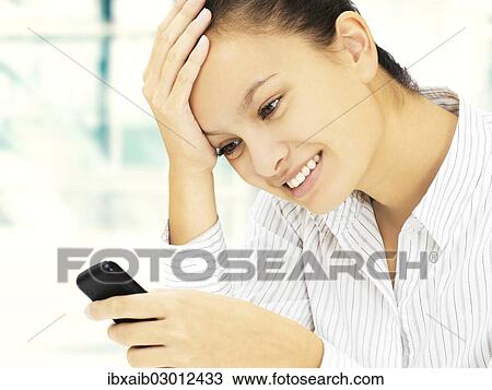 Businesswoman looking pleased while reading an SMS on a mobile phone View Large Photo Image Stock Image - Businesswoman looking pleased while reading an SMS on a mobile phone. Fotosearch