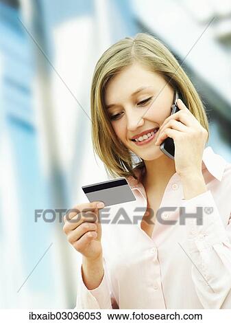 Businesswoman using a mobile phone and holding a card View Large Photo Image Stock Image - Businesswoman using a mobile phone and holding a card. Fotosearch