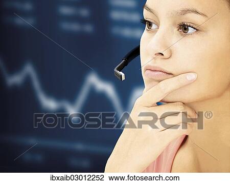 Stock Image - Businesswoman wearing a headset in front of a stock market curve. Fotosearch