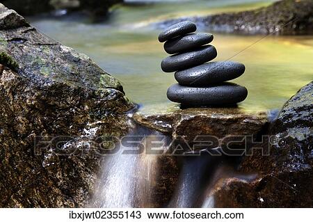 Stock Image - "Cairn, stack of basalt rocks in a creek". Fotosearch