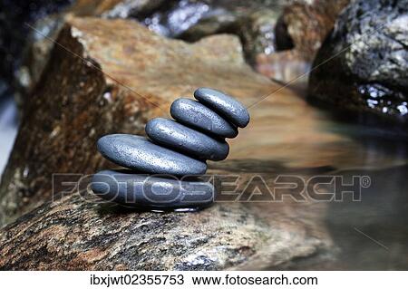 Stock Image - "Cairn, stack of basalt rocks in a mountain stream". Fotosearch