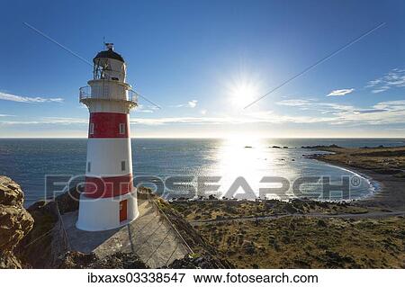 Stock Photo - "Cape Palliser Lighthouse overlooking Kirikiri Bay on the Cook Strait at sunset, Cape Palliser, Wellington Region, New Zealand, Oceania". Fotosearch