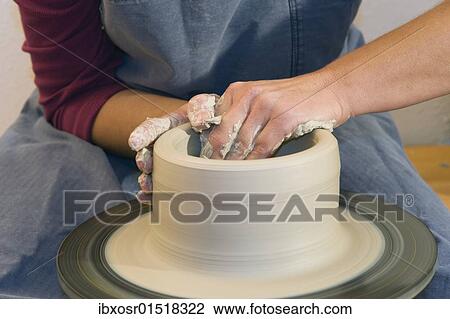 Stock Image - "Ceramic artist working in her workshop with a potter's wheel, pulling a cylinder, Geisenhausen, Bavaria, Germany, Europe". Fotosearch