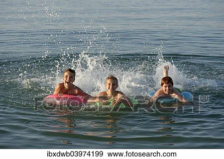 Stock Photo - "Children on floating tyres in the sea, Mediterranean near Fano, Marche, Adriatic, Italy, Europe". Fotosearch