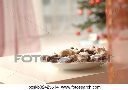 Picture - Christmas cookies on a plate in front of a Christmas tree. Fotosearch