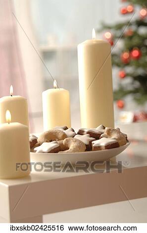 Stock Photograph - "Christmas cookies on a plate, surrounded by candles, in front of Christmas tree". Fotosearch