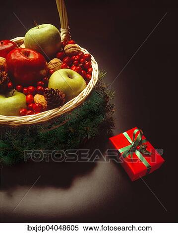 Stock Photography - Christmas present beside festive basket filled with fruits and nuts. Fotosearch