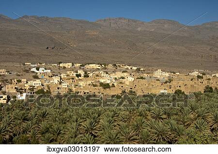 Stock Photo - "City of Al Hamra between green oases with plantations of date palms and the bare slopes of the Jebel Akhdar Mountains, Al Hamra, Ad Dakhiliyah, Oman, Asia". Fotosearch