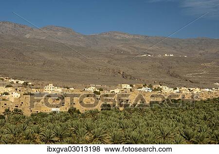 Stock Photo - "City of Al Hamra between green oases with plantations of date palms and the bare slopes of the Jebel Akhdar Mountains, Al Hamra, Ad Dakhiliyah, Oman, Asia". Fotosearch