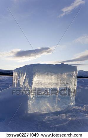 Stock Photo - "Clear ice cube on frozen Fish Lake, cut out with a chain saw, Yukon Territory, Canada, North America". Fotosearch