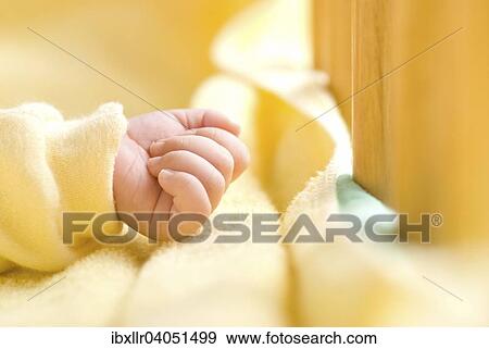 Stock Photo - Clenched baby hand in baby bed. Fotosearch