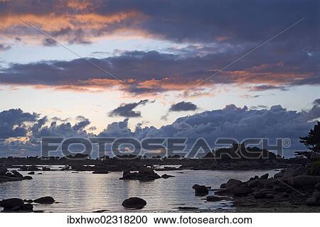 Stock Image - "Cloud formations at sunset over the rocky bay of Sain-Guirec, Ploumanac'h, Cote de Granit Rose, Brittany, France, Europe". Fotosearch