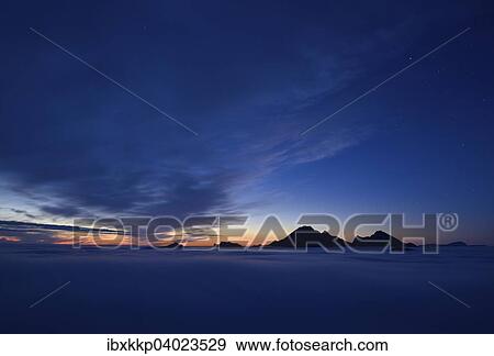 Stock Photo - "Clouds and mountain peaks, view from Offersoykammen at dusk, Lofoten, Norway, Europe". Fotosearch