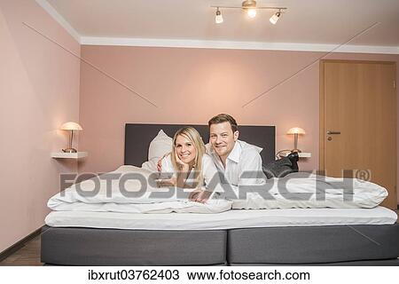 Stock Image - Couple lying on a bed. Fotosearch