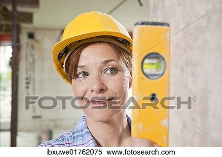 Craftswoman with hard hat checking with a level View Large Photo Image Stock Photography - Craftswoman with hard hat checking with a level. Fotosearch