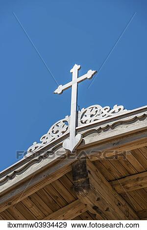 Stock Photo - Crucifix on a wooden roof against a blue sky. Fotosearch