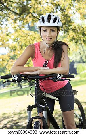 Cycling woman taking a break in the park View Large Photo Image Stock Photo - Cycling woman taking a break in the park. Fotosearch